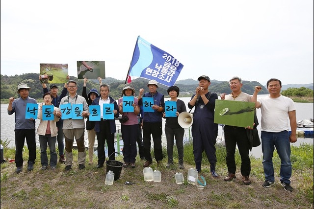 ▲ 현장조사에 나선 활동가와 전문가들이 달성보 상류 둔치에서 낙동강을 흐르게 하라는 손팻말을 들고 외치고 있다. ⓒ이성수