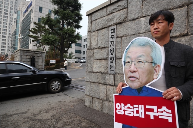 ▲ 김명수 대법원장이 탄 관용 차량이 대구지방법원 앞 정문을 지나고 있다. 이날 한 시민이 "양승태 전 대법원장 구속" 촉구 피켓을 들고 항의 1인 시위를 벌이고 있다(2018.11.7) ⓒ평화뉴스(김영화)