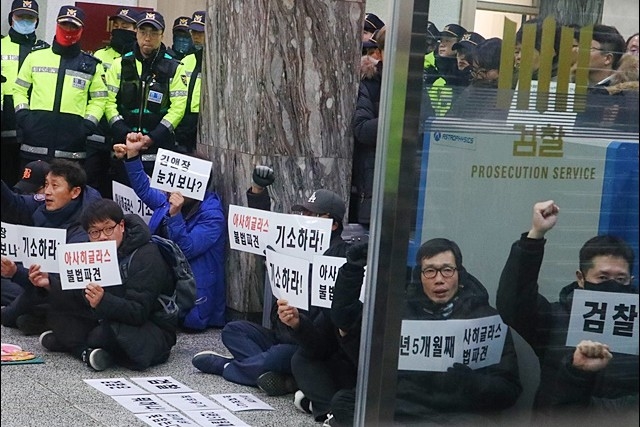 ▲ '불법파견 아사히글라스 검찰은 즉각 기소하라' 대구지방검찰청 로비에서 피켓을 들고 점거농성을 벌이는 경북 구미 아사히글라스 사내하청 비정규직 해고 노동자들(2018.12.27) ⓒ평화뉴스(김영화)