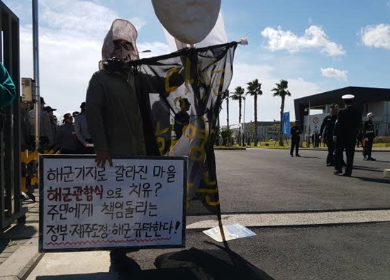 지난해 10월 11일 한 시민활동가가 제주 서귀포시 제주해군기지 정문 앞에서 피켓을 들고 서 있다. ⓒ박해송 기자