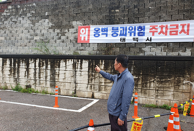 ▲11일 태백시 관계자가 태백역 인근 공영주차장 옹벽에 붕괴위험지역을 설명하고 있다. ⓒ프레시안