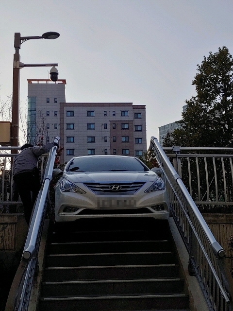 ▲ 공원 내 계단에 걸쳐져 있는 소나타 차량. ⓒ부산경찰청